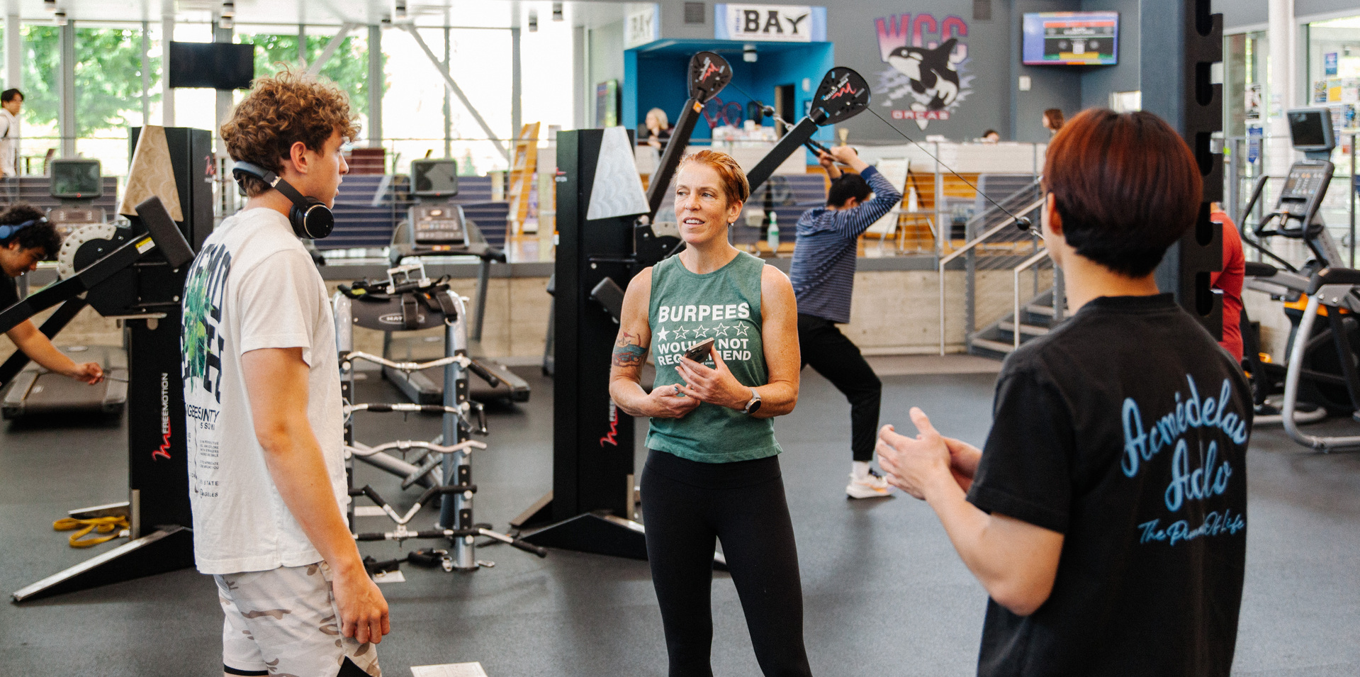 Fitness instructor speaking with students in weight lifting area of SRC