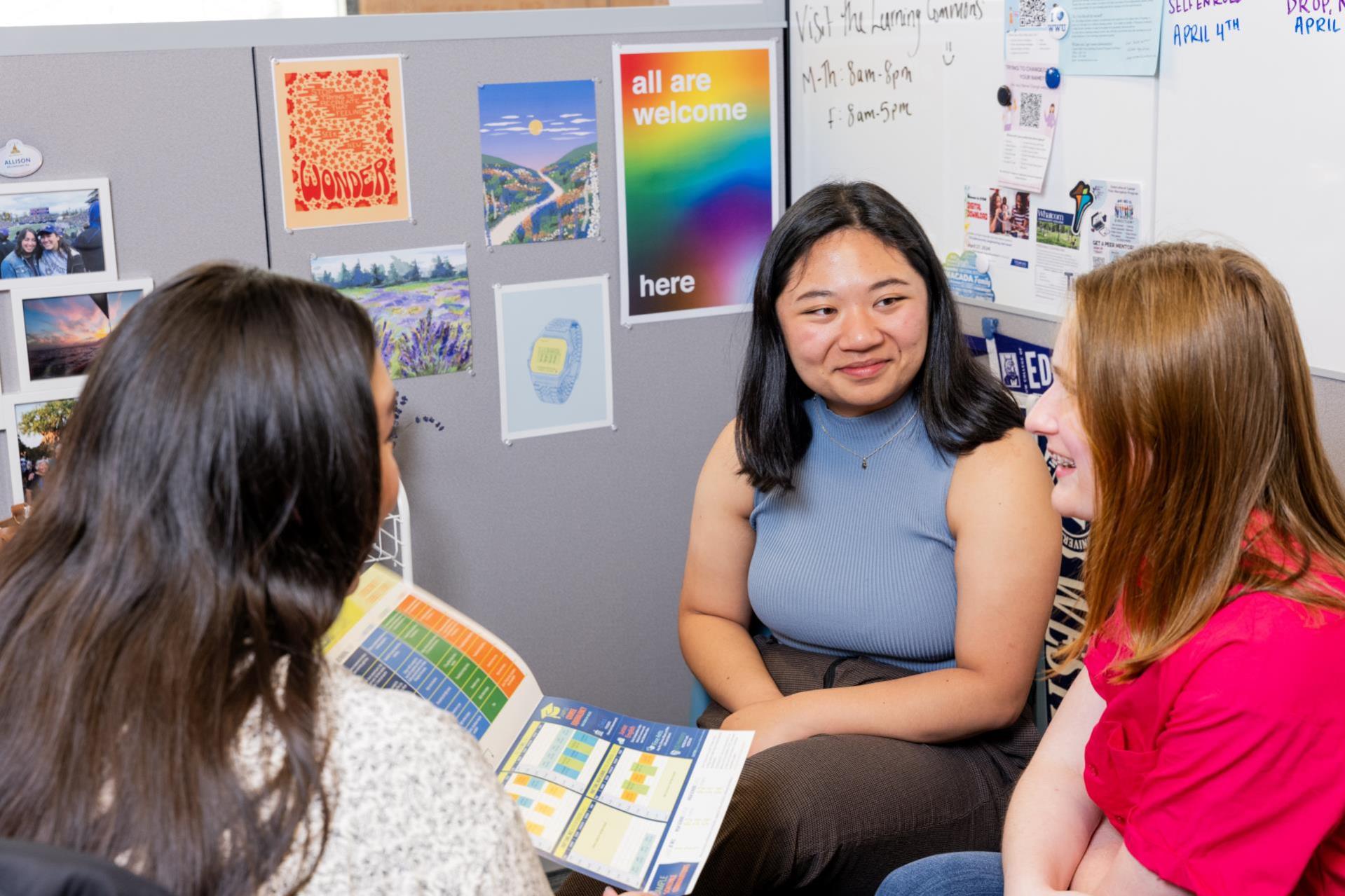 A staff member explaining a booklet to two WCC students